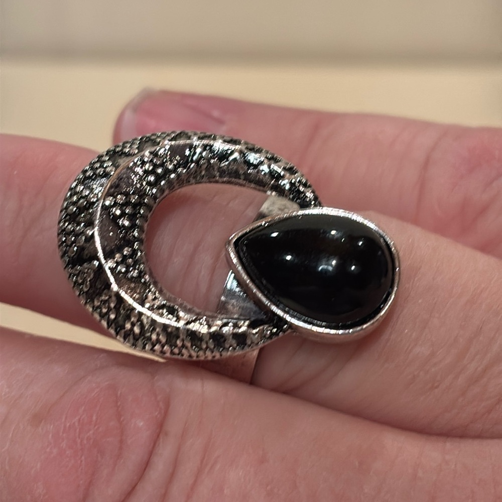 Ring size 7 adjusts up to larger size. Silver toned and black acrylic center.
